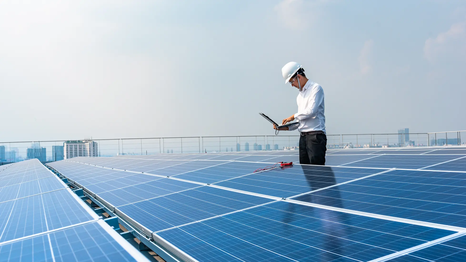 Technician using a laptop to run performance tests on commercial solar panels.