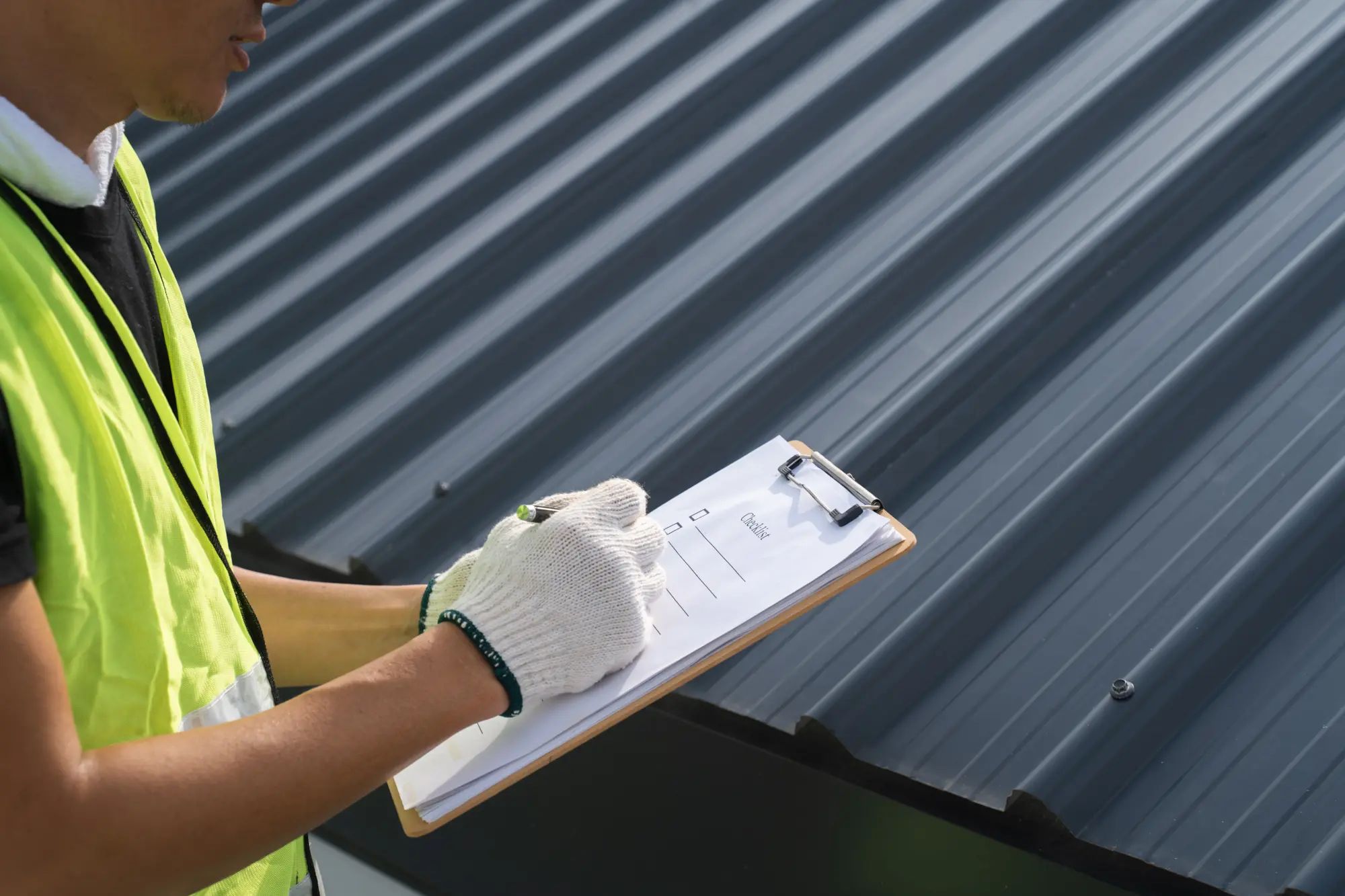 Technician inspecting rooftop during commercial solar site evaluation with clipboard.